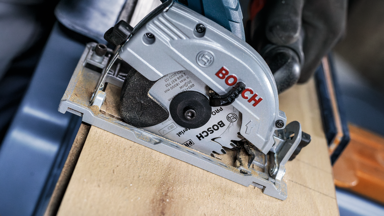 配戴安全設備的人員使用圓鋸切割木材。