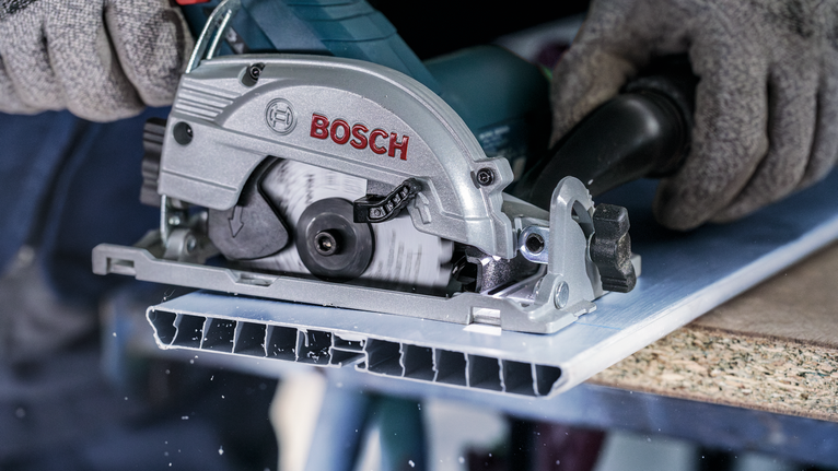 配戴安全設備的人員用圓鋸切割金屬板。