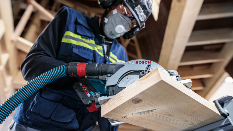 配戴安全設備的人員用圓鋸切割木板。