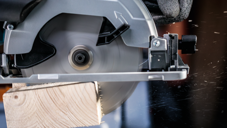 配戴安全設備的人員用圓鋸切割木板。