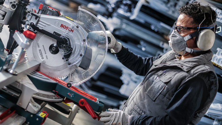配戴安全設備的人員在車間調整圓鋸。
