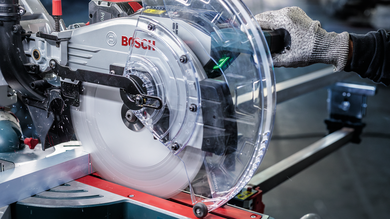 配戴安全設備的人員在金屬切割工作站上操作圓鋸。