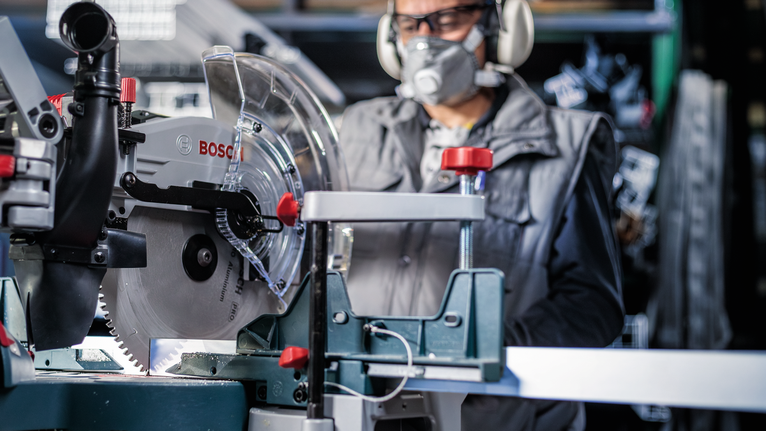一名配戴安全設備的人員在車間操作圓鋸。