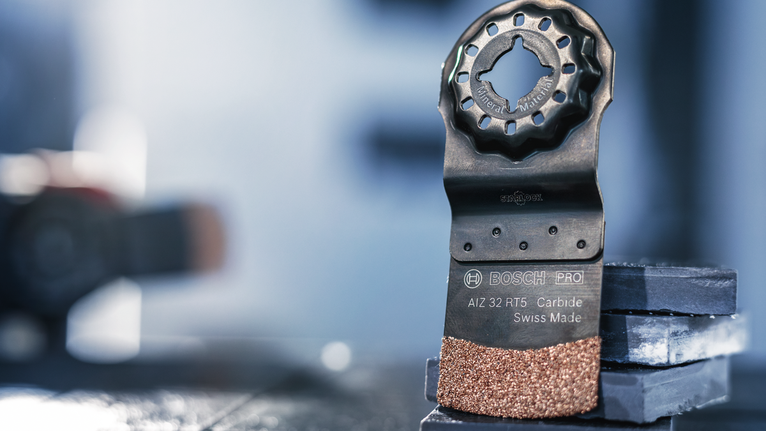 振盪多工具硬質合金刀片直立在堆疊的磁磚上。