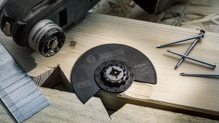 用於木材切割的圓鋸片附件放置在木板上，附近有釘子。