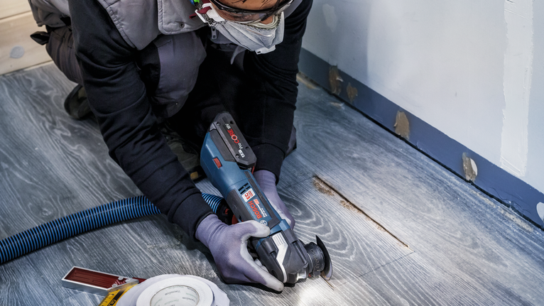 配戴安全設備的人員使用電動工具切割木地板。