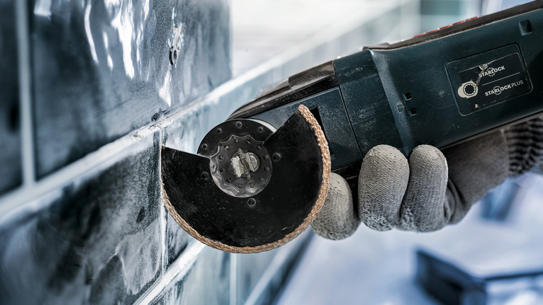 一名配戴安全設備的人員使用電動工具切割磁磚。