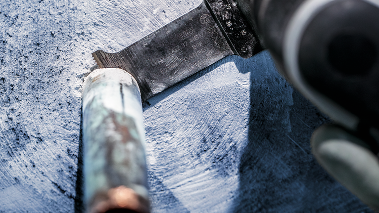 配戴安全設備的人員使用往復鋸切割金屬管路。