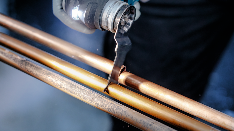 一名工人使用振盪工具切割銅管。