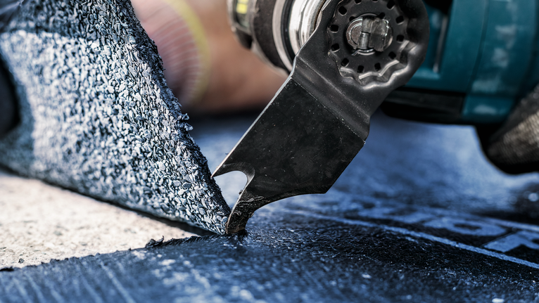 一名配戴安全設備的人員使用電動工具切割地板材料。