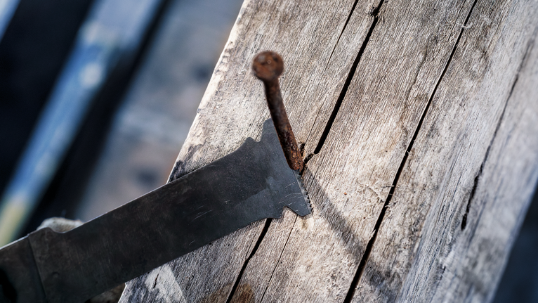 往復鋸片切割嵌入舊木頭的生鏽釘子。