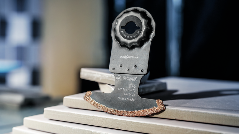 帶有硬質合金刀刃的振動工具刀片放置在堆疊的瓷磚上。