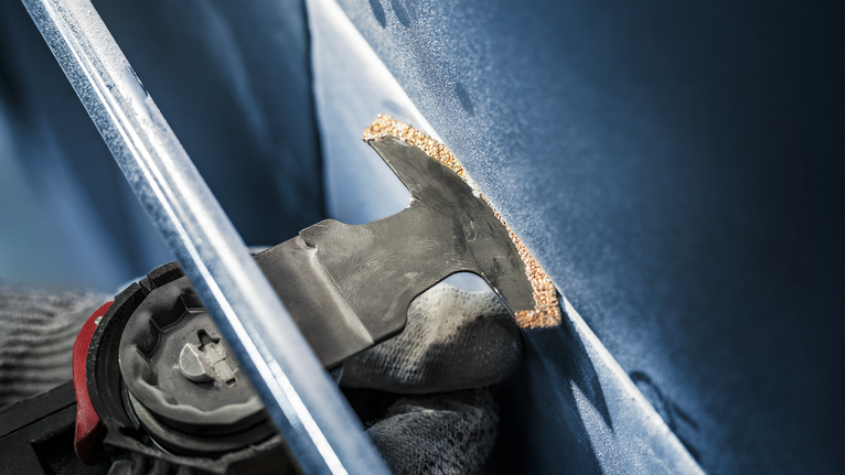 配戴安全設備的人員使用振盪工具切割面板。