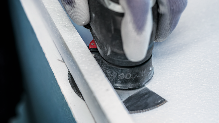 配戴安全設備的人員使用多用途刀片切割面板。