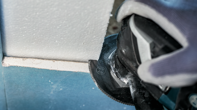 配戴安全設備的人員使用電動工具切割石膏板。