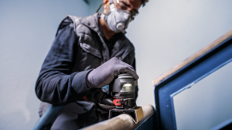 配戴安全設備的人員使用電動工具打磨金屬扶手。