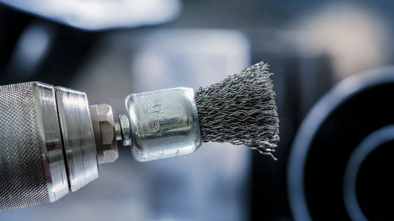 PRO Metal clean 端刷,直柄,25 x 0.3 mm 裝有鋼絲刷附件的電鑽的特寫。