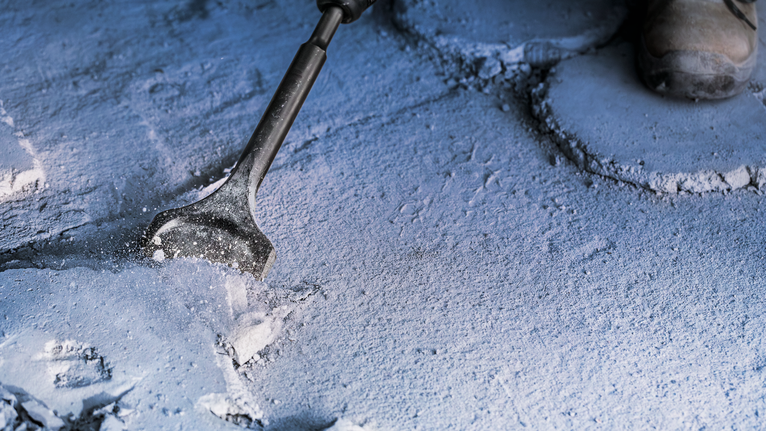 配戴安全設備的人員鑿開混凝土表面。