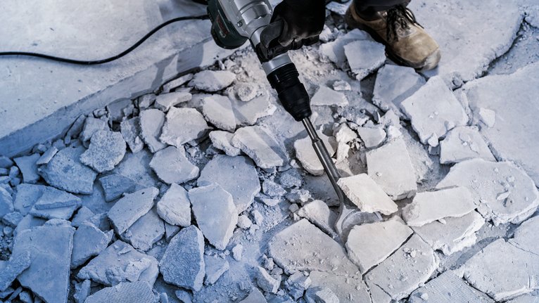 配戴安全設備的人員用破碎錘打破混凝土地板。