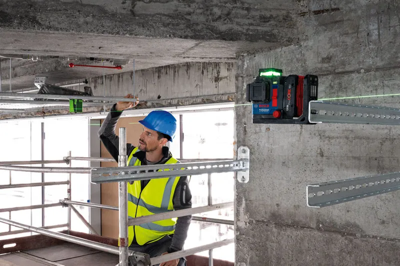 一名配戴安全設備的人員使用雷射調平工具對準金屬棒。.