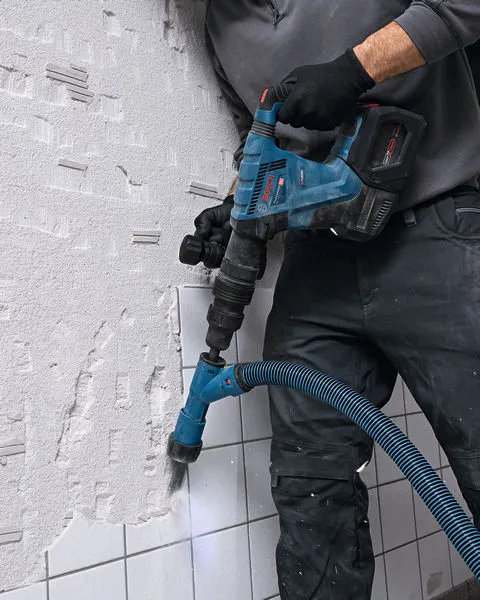 GSH 18V-5 一名配戴安全裝備的人員使用無線破碎鎚砸碎牆磚。.