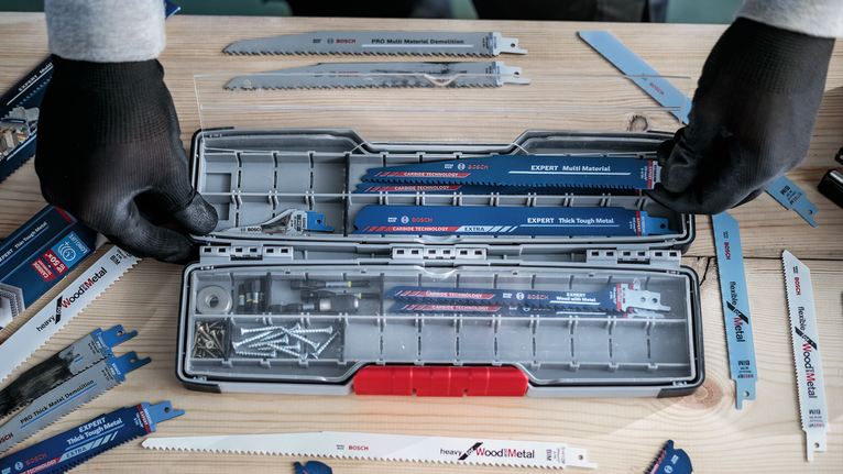 配戴安全設備的人員將鋸片和螺絲整理到工具箱。