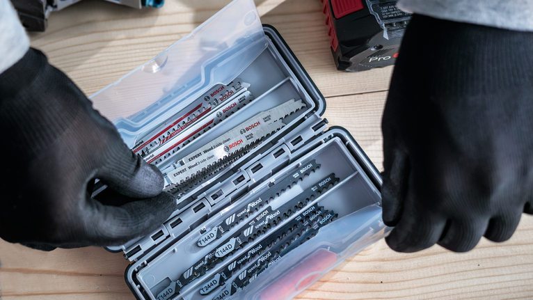 佩戴安全設備的人員從木質表面上的塑膠盒中選擇鋸片。