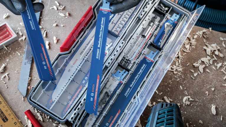 配戴安全設備的人員在佈滿灰塵的工作檯面上從盒子裡選擇鋸片。