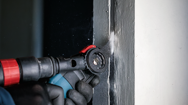 配戴安全設備的人員使用電動工具切開門框。