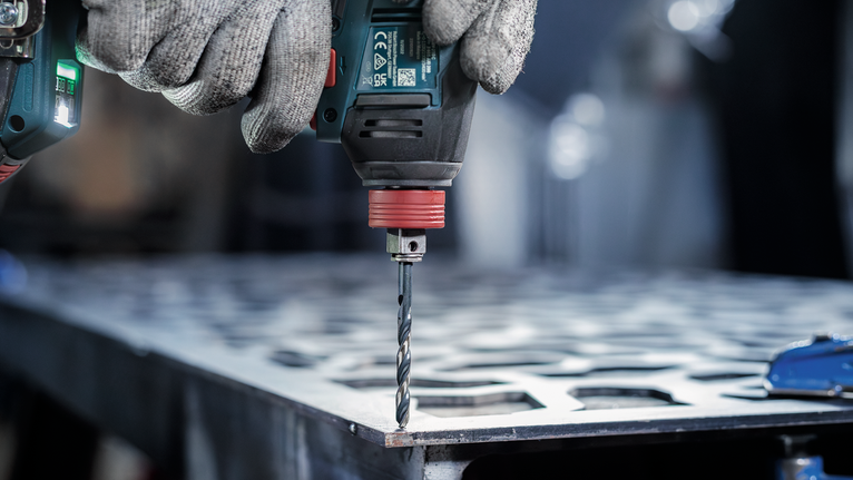 配戴安全設備的人員正在鑽金屬板。