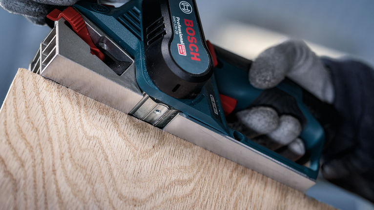 穿著安全裝備的人刨木板的邊緣。