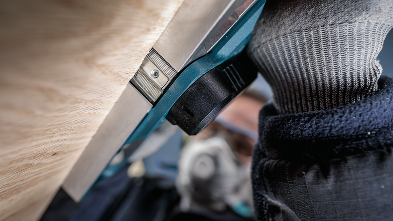 配戴安全設備的人員在靠近木質表面的地方操作電動工具。