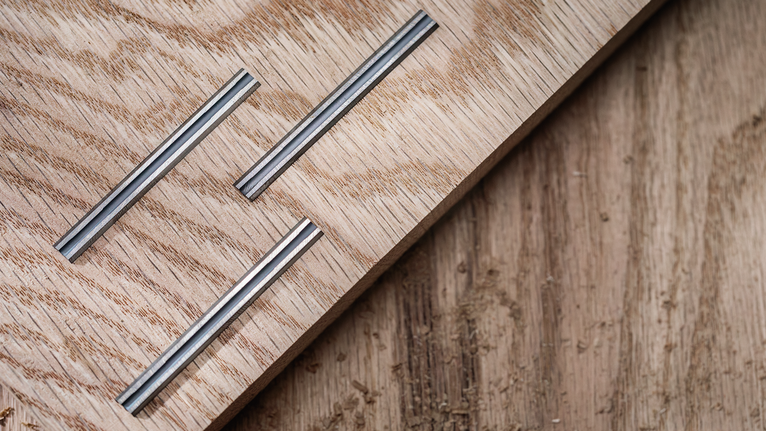 三個凹槽金屬鑲嵌物嵌入淺色木板中。