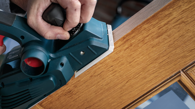 電動刨床正在打磨木門的邊緣。.