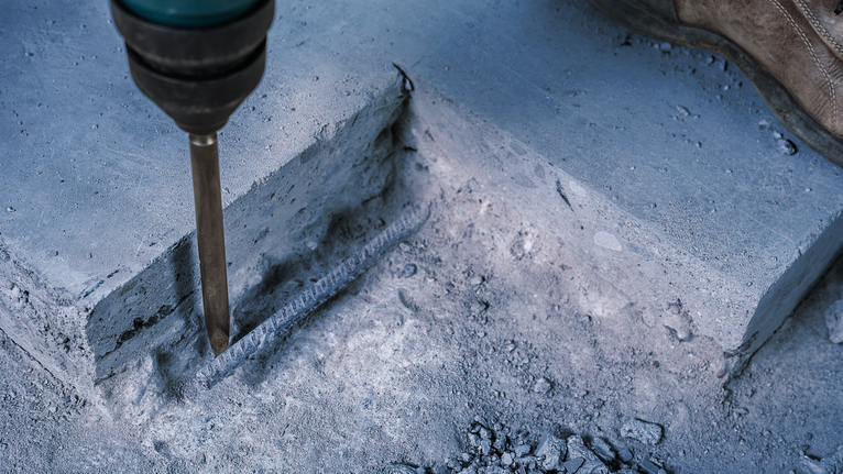 PRO SDS plus-4C 鑿子尖角鑿刀,160 mm 配戴安全設備的人員使用拆除工具破碎混凝土。