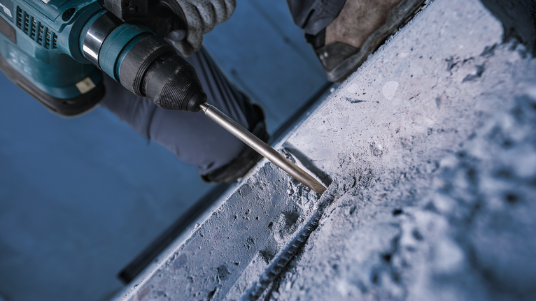 PRO SDS plus-4C 鑿子尖角鑿刀,160 mm 配戴安全設備的人員使用旋轉鎚鑽入混凝土。