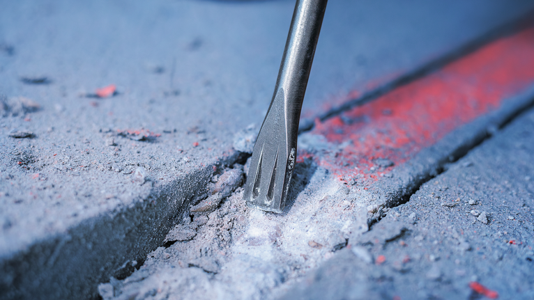 鑿子鑽頭沿著標記線破碎混凝土。