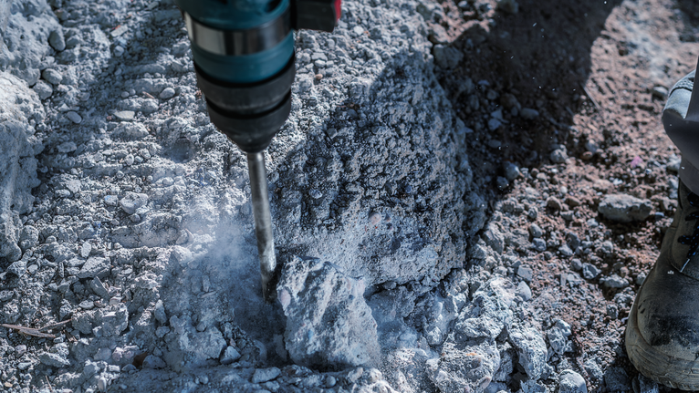 錘鑽突破粗糙的混凝土，工人配戴安全設備。.