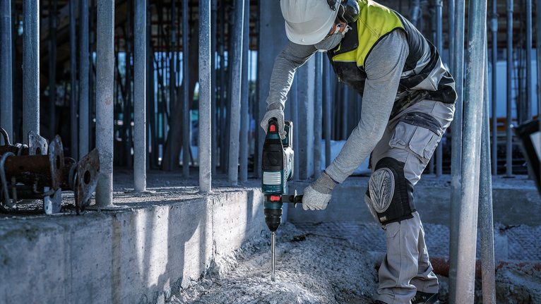 一名佩戴安全設備的人員使用旋轉錘破碎混凝土。