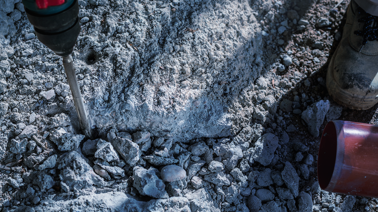 一名佩戴安全設備的人員使用旋轉錘破碎混凝土。