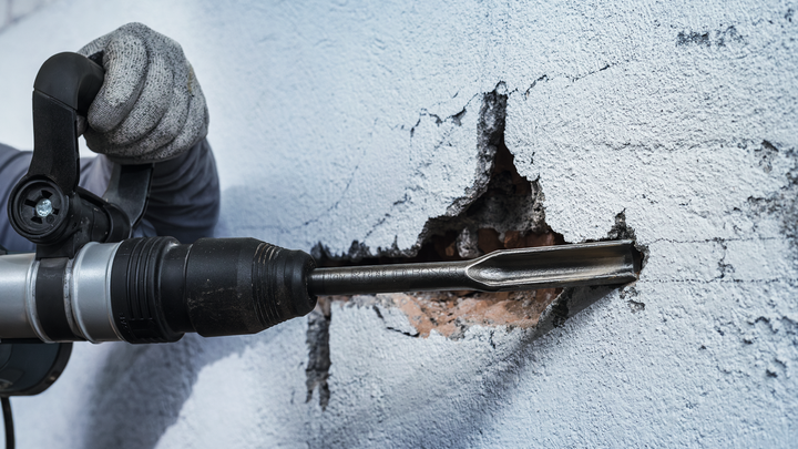 Object #200465502: 3093775_app_web_01 一名佩戴安全設備的人使用旋轉錘鑿牆。