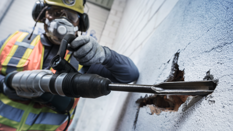 PRO SDS max 鋸齒鏜孔鑿刀,26 x 300 mm 配戴安全設備的人員使用旋轉錘打破混凝土牆。