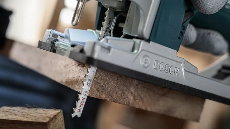 配戴安全設備的人員使用曲線鋸切割木板。