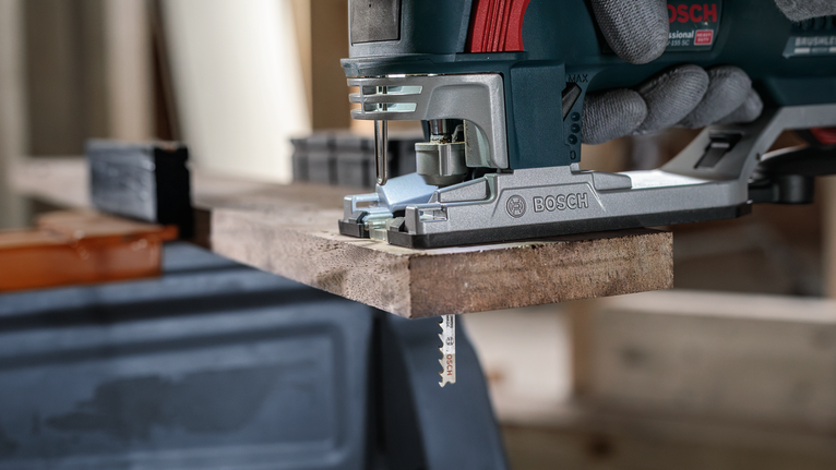 配戴安全設備的人員使用曲線鋸切割木板。