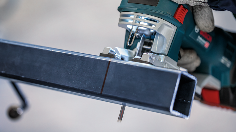 配戴安全設備的人員使用曲線鋸切割金屬梁。