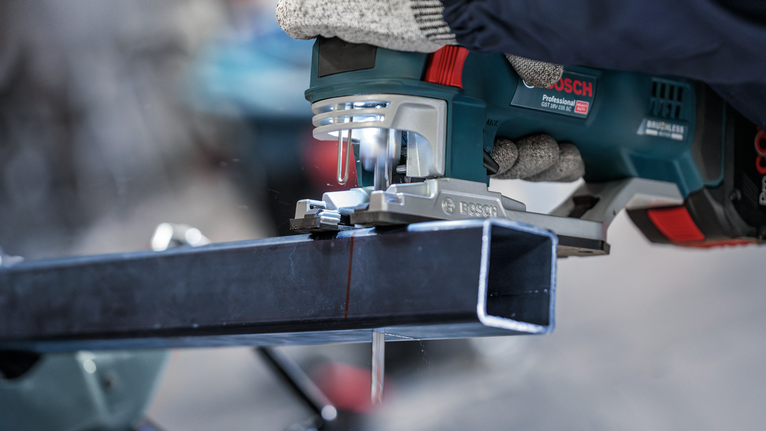 配戴安全設備的人員使用手持電鋸切割金屬梁。