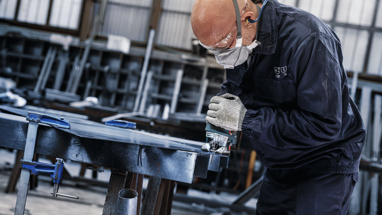 PRO Metal thick and thin T123XF 線鋸片,100 mm,3 件 配戴安全設備的人員在車間使用電鋸切割金屬。