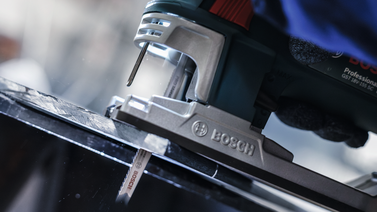 PRO Metal thick and thin T123XF 線鋸片,100 mm,3 件 一名佩戴安全設備的人使用曲線鋸切割黑色金屬板。