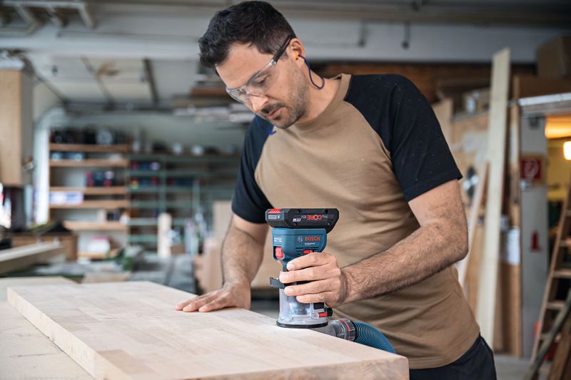 一名配戴安全設備的人員使用無線掌上路由器對木板的邊緣進行佈線。.