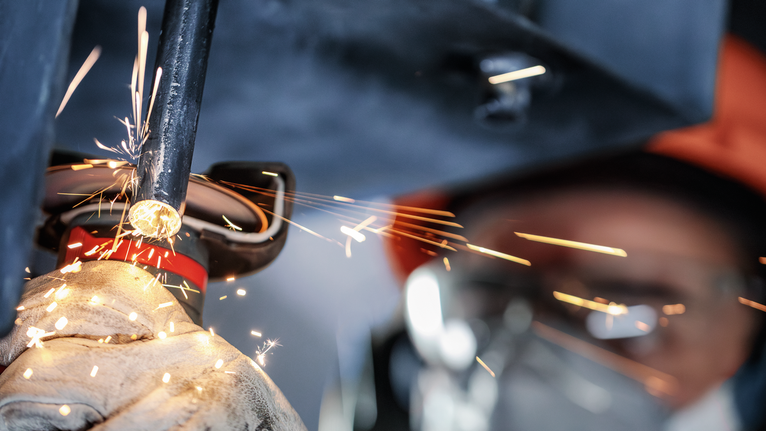 配戴安全設備的人員研磨金屬管，產生明亮的火花。